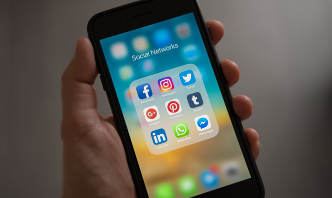 to represent the importance for omnichannel customer service this image shows a white hand holding a phone with social network icons on it