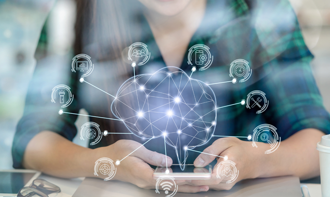 A graphic of a brain with lots of icons coming from it floating over the top of a phone held by a young feminine person.